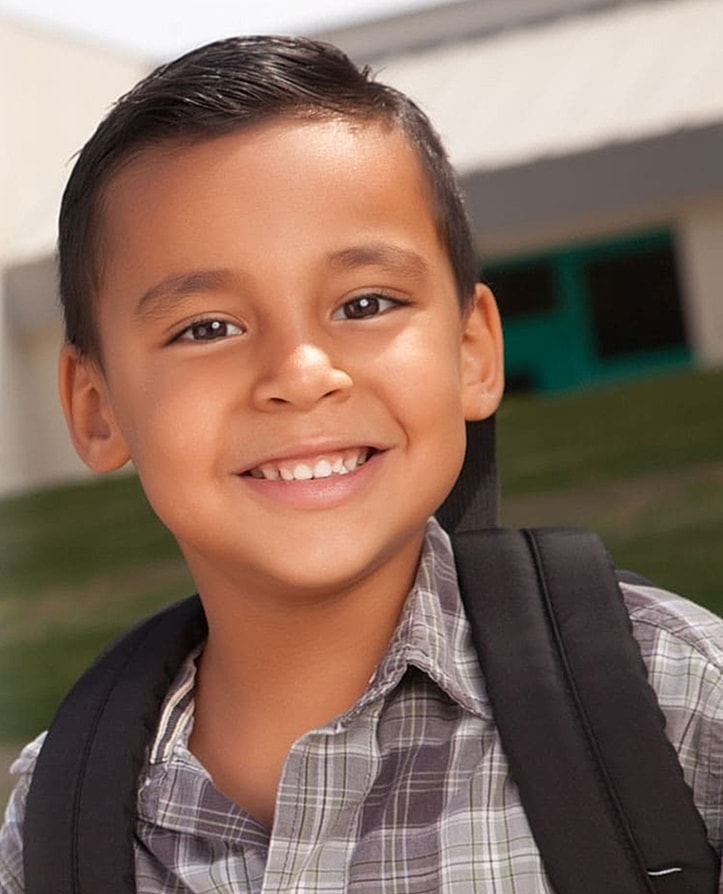 Smiling boy with backpack in outdoor setting.