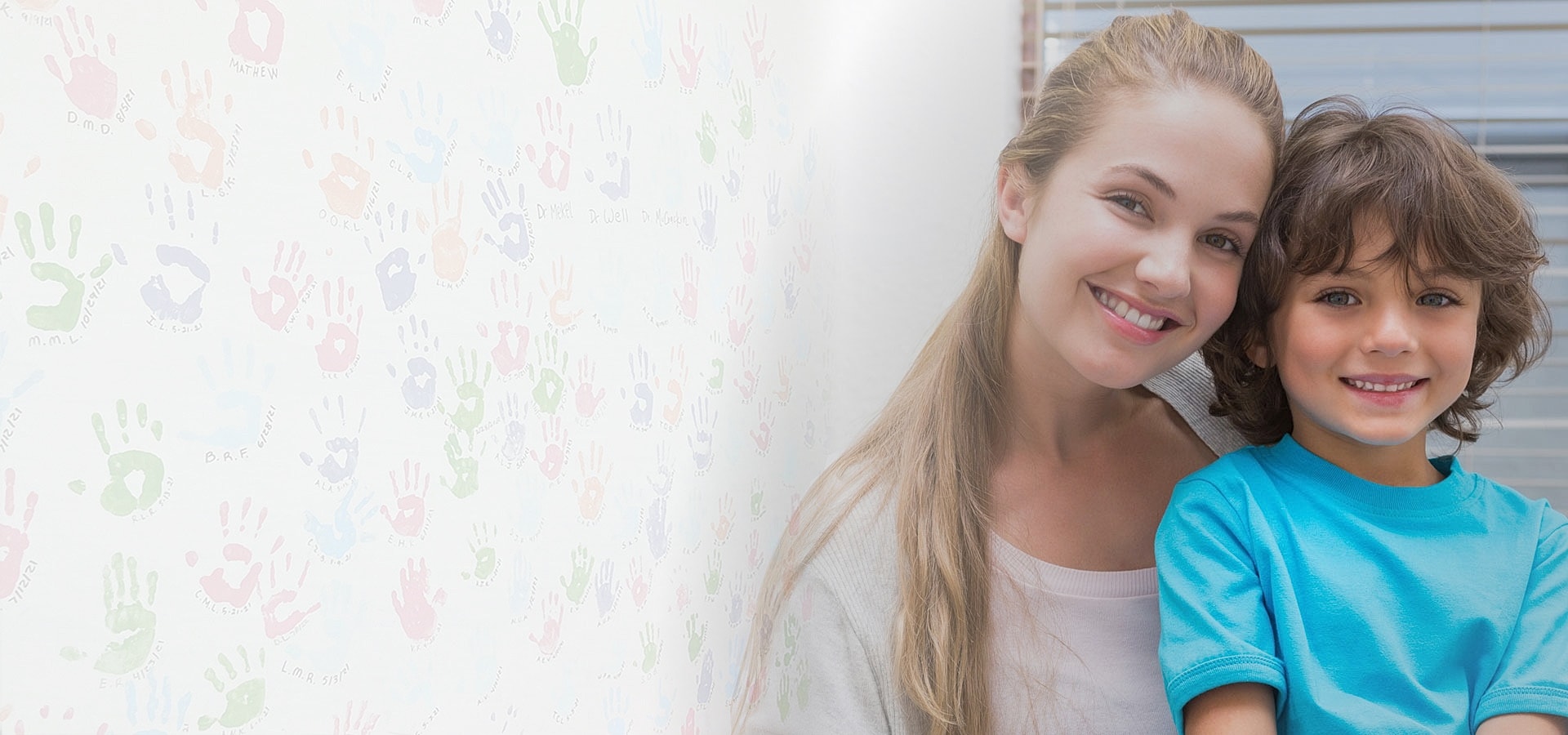 Smiling woman and child with colorful handprints background.