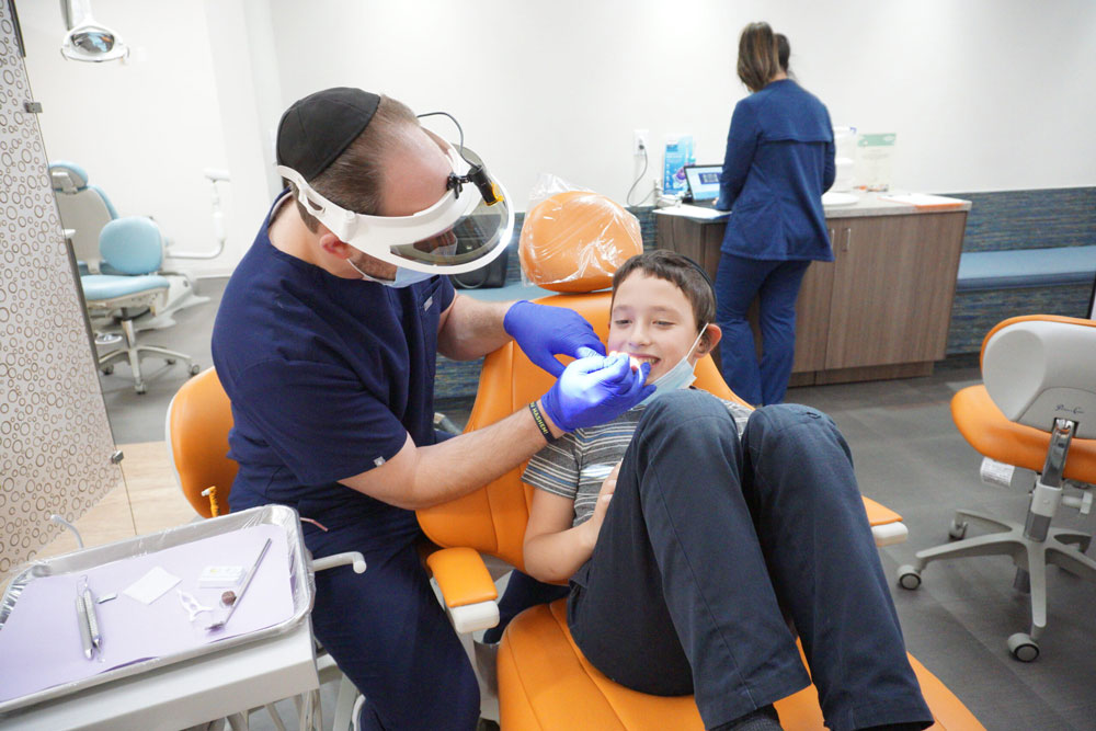 dr dan performing teeth cleaning on young patient